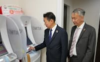 新型ATMを操作する北陸銀の小林取締役と、セブン銀の松橋社長（20日、富山市）