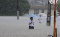大雨の影響で冠水した道路を歩く人＝7月、福岡県久留米市