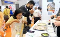 インドの首都ニューデリーで開かれた食品展示会で、日本産のホタテやハマチの刺し身を試食する人たち＝11月3日（NNA＝共同）