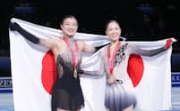 フィギュアスケートのグランプリファイナル女子で優勝し、日の丸を掲げる坂本花織（左）と3位の吉田陽菜（9日、北京）＝共同