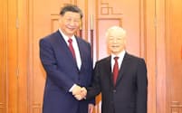 12日、ベトナムの首都ハノイでチョン共産党書記長㊨と握手する中国の習近平国家主席＝VNA・共同
