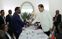 握手するベネズエラのマドゥロ大統領㊨とガイアナのアリ大統領（14日、セントビンセント・グレナディーン）＝ロイター