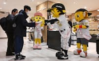 阪神タイガースの福袋をマスコットのトラッキーから受け取る買い物客（2日、大阪市の阪神梅田本店）