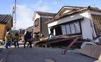 余震が発生し、捜索を中断して倒壊した建物から飛び出す警察官ら＝2日午前11時5分、石川県輪島市