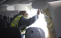 ７日、アラスカ航空機の側壁を調べる航空安全当局の職員＝ＡＰ
