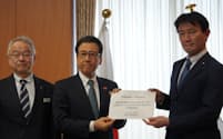札幌市の秋元市長㊥が提案書を手渡した（23日、東京・千代田）