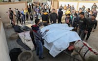 イスラエル軍の攻撃による犠牲者の遺体を運ぶ人々（23日、ガザ南部ハンユニス）＝ロイター