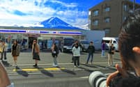 ローソンの前にはポーズをとる観光客が並ぶ。富士山が屋根のようでかわいいらしい（山梨県富士河口湖町）