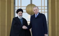 24日、アンカラで握手するイランのライシ大統領㊧とトルコのエルドアン大統領＝ロイター