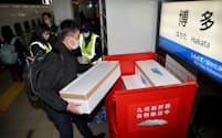 鹿児島から新幹線で運ばれてきたブリの入った箱を台車へ積む職員（1月、JR博多駅）