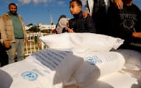 ＵＮＲＷＡが配布する小麦粉を受け取るパレスチナ自治区ガザの住民（2023年11月）＝ロイター