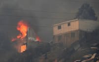 3日、森林火災が起きたチリ中部バルパライソ郊外で燃える家屋（ロイター＝共同）