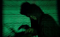 FILE PHOTO: A hooded man holds a laptop computer as cyber code is projected on him in this illustration picture taken on May 13, 2017. Top U.S. fuel pipeline operator Colonial Pipeline has shut its entire network after a cyber attack, the company said on Friday. REUTERS/Kacper Pempel/Illustration/File Photo
