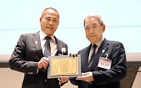 関西財界セミナー賞の大賞を受賞し、記念撮影に応じるたねやの山本昌仁社長（左）。右は関経連の松本正義会長（9日、京都市左京区）