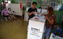 浸水した投票所で一票を投じる有権者（14日、ジャカルタ）＝Antara Foto氏、Wahyu Putro氏提供・ロイター