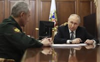 20日、モスクワのクレムリンでショイグ国防相（左）の報告を受けるプーチン氏＝AP