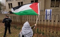 在米イスラエル大使館前でパレスチナの旗を振って抗議する人（2023年12月、ワシントン）＝ロイター