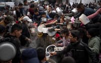 パレスチナ自治区ガザ南部のラファで食事を受け取る列に並ぶ住民（2023年12月）＝ＡＰ