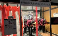 店舗入り口に幕がひかれる中、頭を下げる店長と従業員ら（29日、名古屋市）