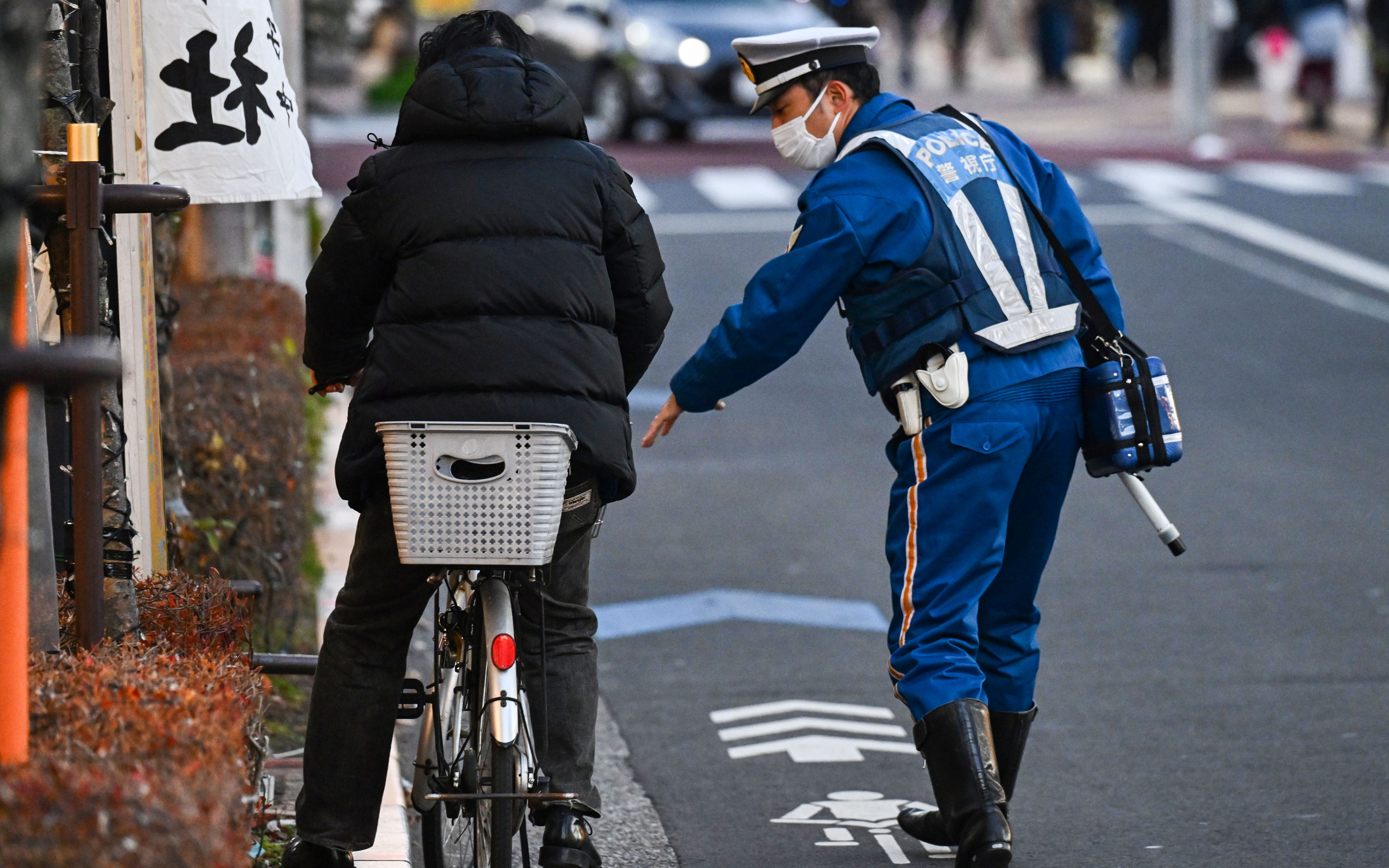 自転車の交通違反者を取り締まる警察官（2023年12月、東京都江戸川区）