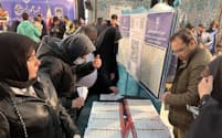 1日、テヘラン北部の投票所で立候補者のリストから投票先を選ぶ有権者ら