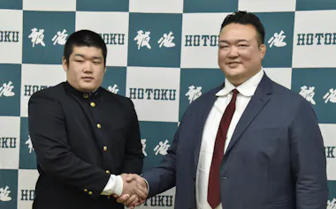報徳学園高を訪問した筆者(右)と握手して撮影に応じる新弟子の今村(1日)=共同
