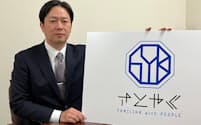「さとやく」の新たなブランドロゴを掲げる佐藤社長（奈良県橿原市）