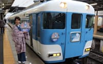 近鉄の特別列車のヘッドマークを持つ新竹商店の新竹浩子社長（３月２４日、三重県松阪市）