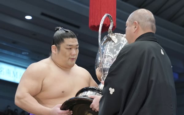 大相撲春場所で110年ぶりとなる新入幕優勝を果たし、日本相撲協会の八角理事長(右)から賜杯を受け取る尊富士=共同