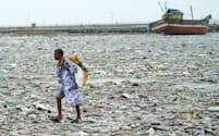 海岸に打ち上げられたプラスチックごみを集める男性（インド・ムンバイ近郊）