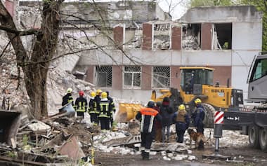 ロシア軍の攻撃で破壊された建物で、がれきの除去作業に当たる重機（17日、ウクライナ北部チェルニヒウ）=共同
