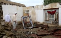 被害を受けた家に散乱する窓枠を片付けるアフガニスタンの男性（15日）＝ロイター