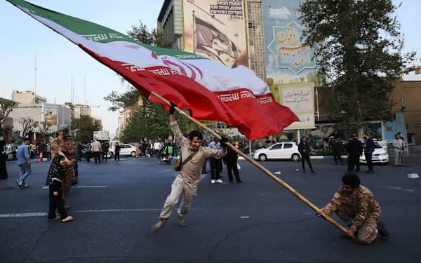 巨大なイラン国旗を振り回すデモ隊（15日、テヘラン）=AP