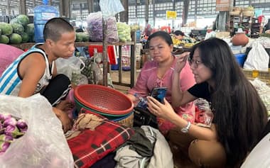零細事業者にデジタル活用を指南するMAEXのスタッフ（右、3月、ヤンゴン北部の青果卸売市場）