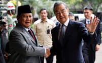 インドネシア次期大統領のプラボウォ国防相㊧と握手する中国の王毅外相（18日、ジャカルタ）＝ロイター