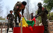 国軍の拠点でミャンマー国旗を燃やす少数民族武装勢力の兵士（15日、ミャワディ郊外）＝ロイター