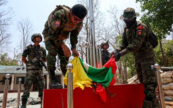 国軍の拠点でミャンマー国旗を燃やす少数民族武装勢力の兵士（15日、ミャワディ郊外）=ロイター