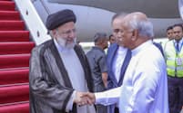 スリランカのグナワルダナ首相㊨に出迎えられるイランのライシ大統領（4月24日）＝スリランカ大統領府提供・AP