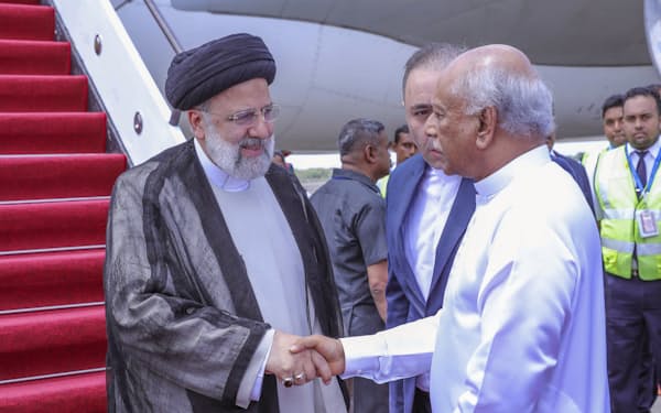 スリランカのグナワルダナ首相㊨に出迎えられるイランのライシ大統領（4月24日）=スリランカ大統領府提供・AP