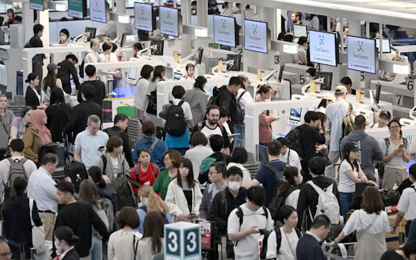 羽田空港の国際線出発カウンターで手続きをする人たち（27日午前）