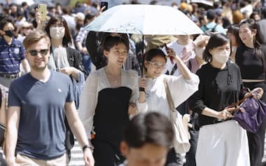 東京・渋谷のスクランブル交差点を日傘を差して歩く人たち（28日午後）=共同