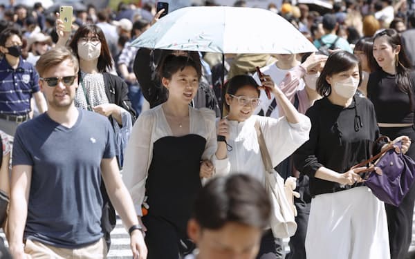 東京・渋谷のスクランブル交差点を日傘を差して歩く人たち=28日午後