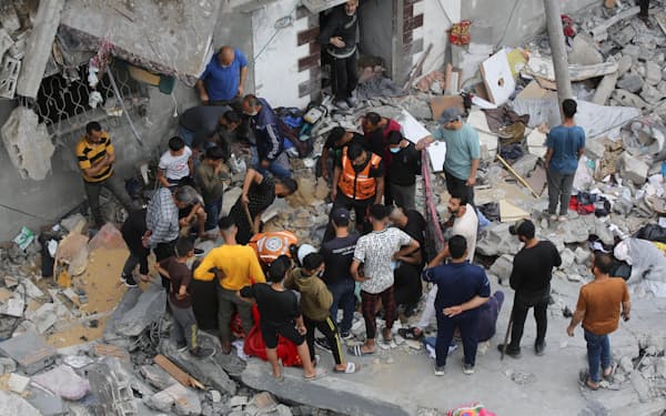 27日、ガザ地区中部デールバラハへのイスラエル軍の攻撃後、破壊された建物付近で救助に当たる人々（ゲッティ共同）