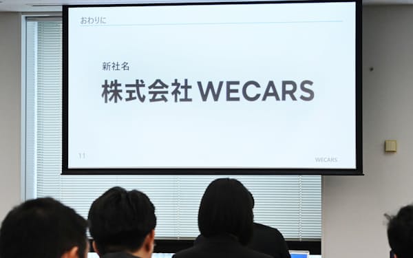 記者会見でスクリーンに映し出された、ビッグモーターから事業を継承した新会社の社名「WECARS」（1日午前、東京都港区）