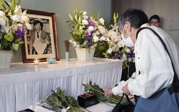 朝日新聞阪神支局に設けられた小尻知博記者の祭壇に、花を手向ける地元住民（3日、兵庫県西宮市）=共同