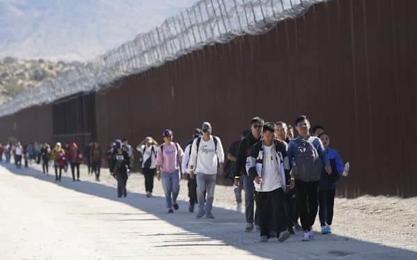 国境沿いの壁を歩く移民たちのなかに多数の中国系も混じっている(2023年10月末)=AP
