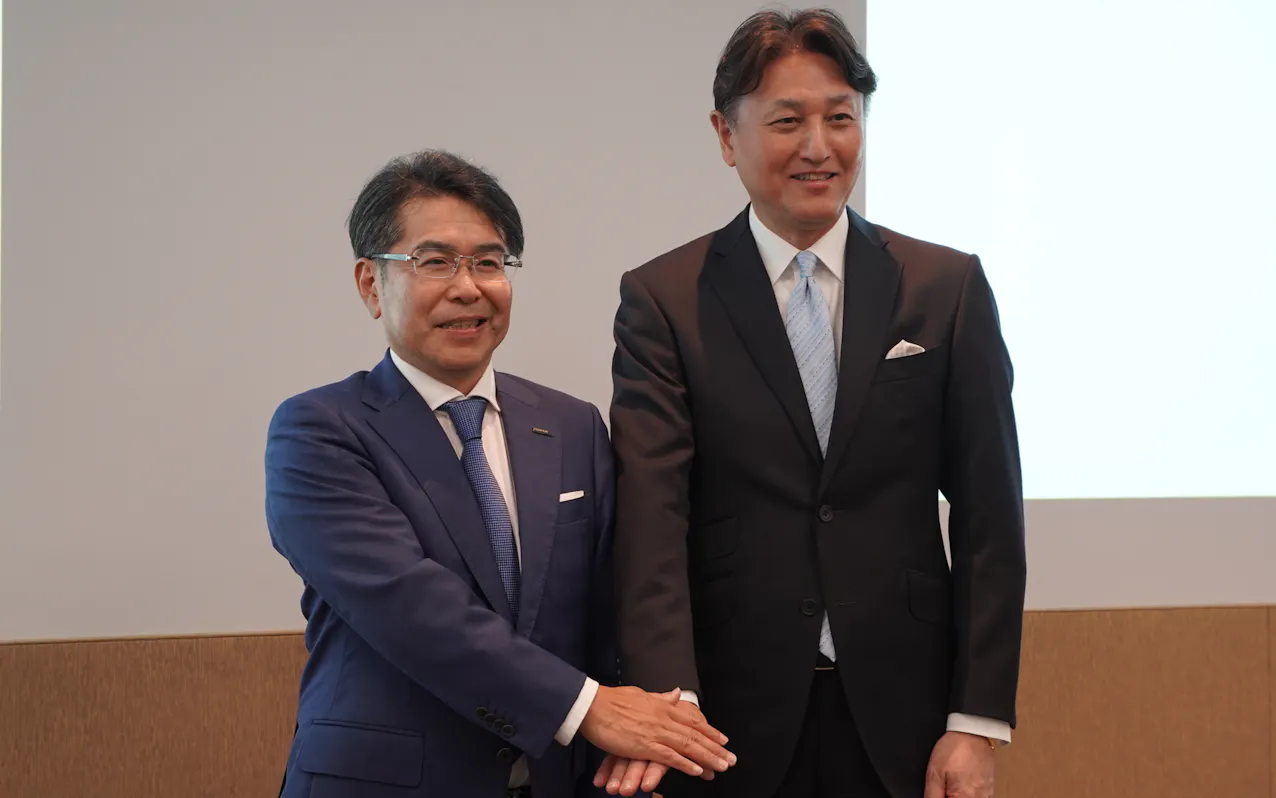 記者会見で撮影に応じる富士フイルムBIの鍋田CTO㊧とAWSジャパンの堤浩幸・常務執行役員(15日、東京都港区)