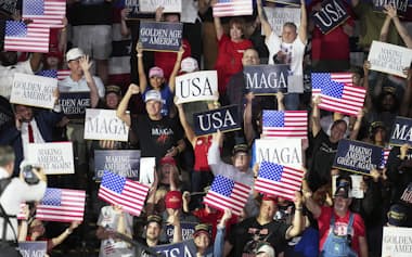 4月、ミシガン州の大学で演説するトランプ大統領を、MAGAのプラカードを掲げて迎える聴衆=AP