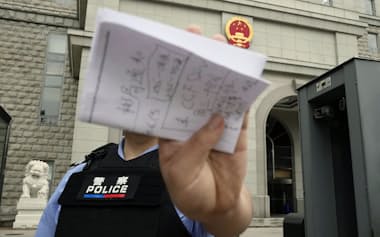 スパイ罪で起訴された日本人男性の判決公判が開かれた北京市の第2中級人民法院前で撮影を阻止する警察官(16日)=共同
