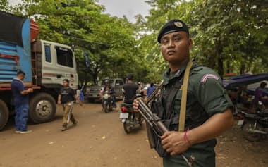 武装して補給トラックを守るカンボジア国家警察の警官(27日、カンボジア)=AP